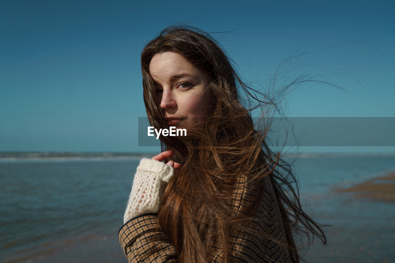 Portrait of woman on beach against sky