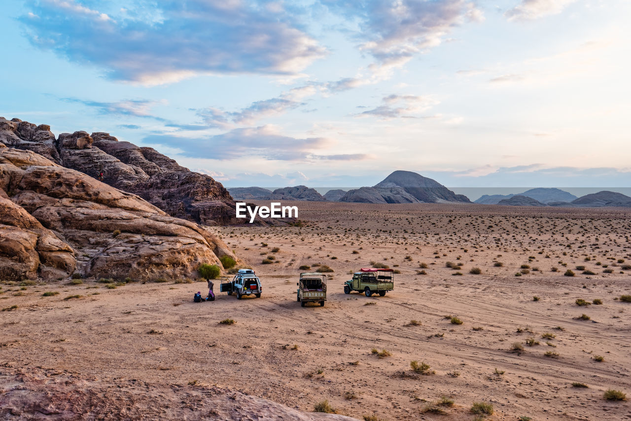 Off-road vehicles at desert against sky