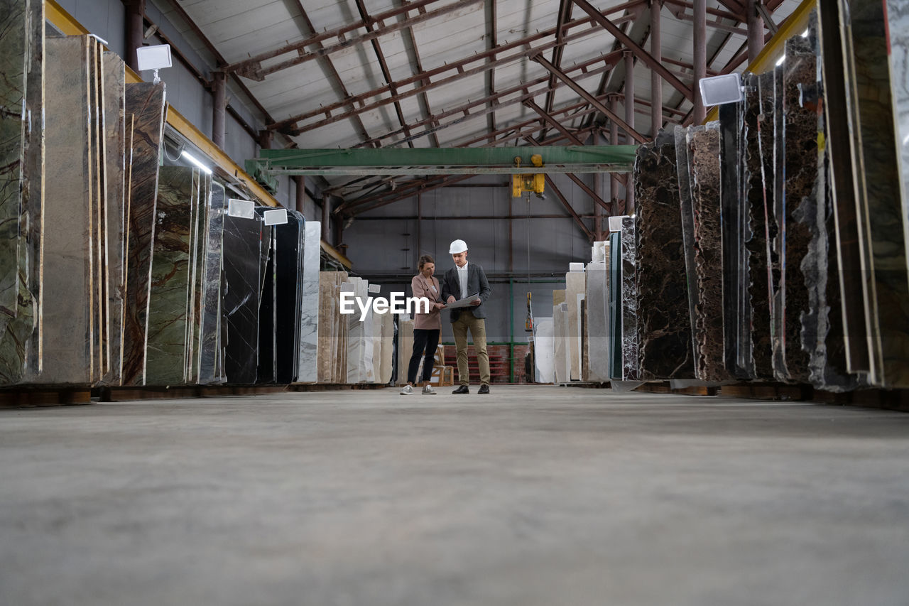 Architects discussing blueprint in warehouse