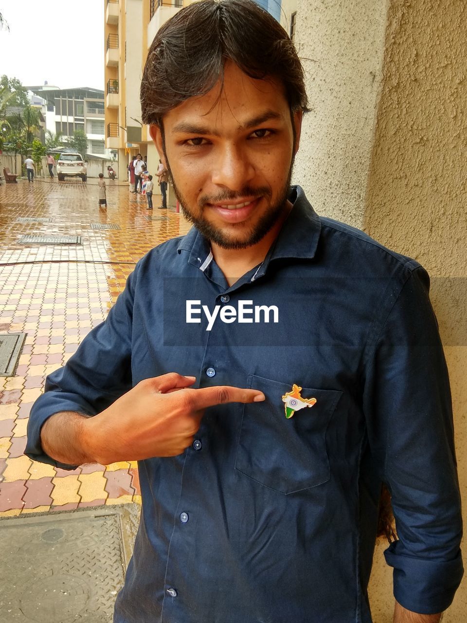 PORTRAIT OF SMILING YOUNG MAN STANDING ON SMART PHONE