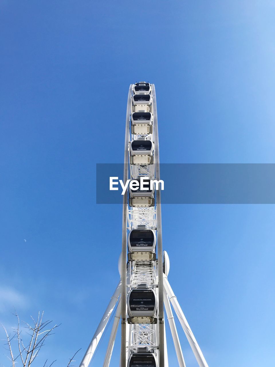 Low angle view of ferris wheel against clear blue sky