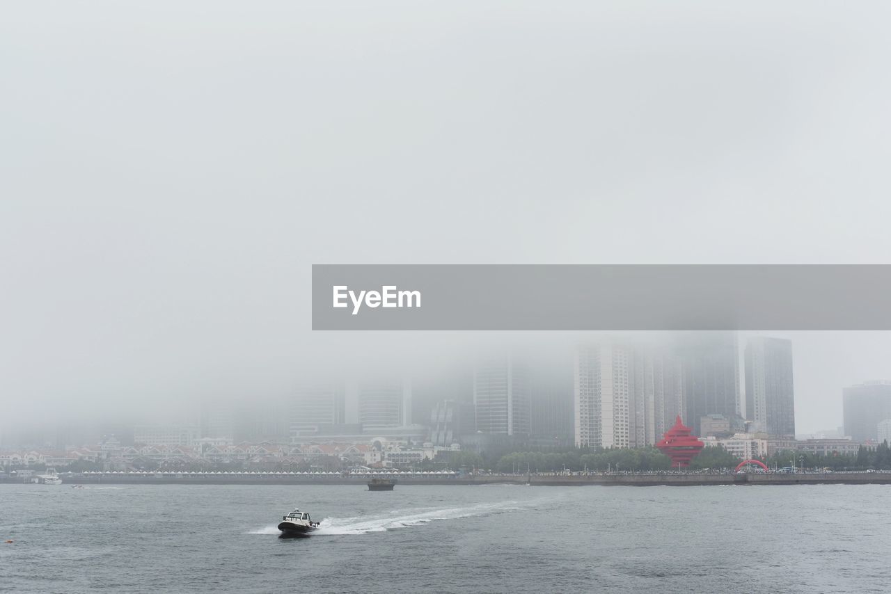 Boat in river with city in background