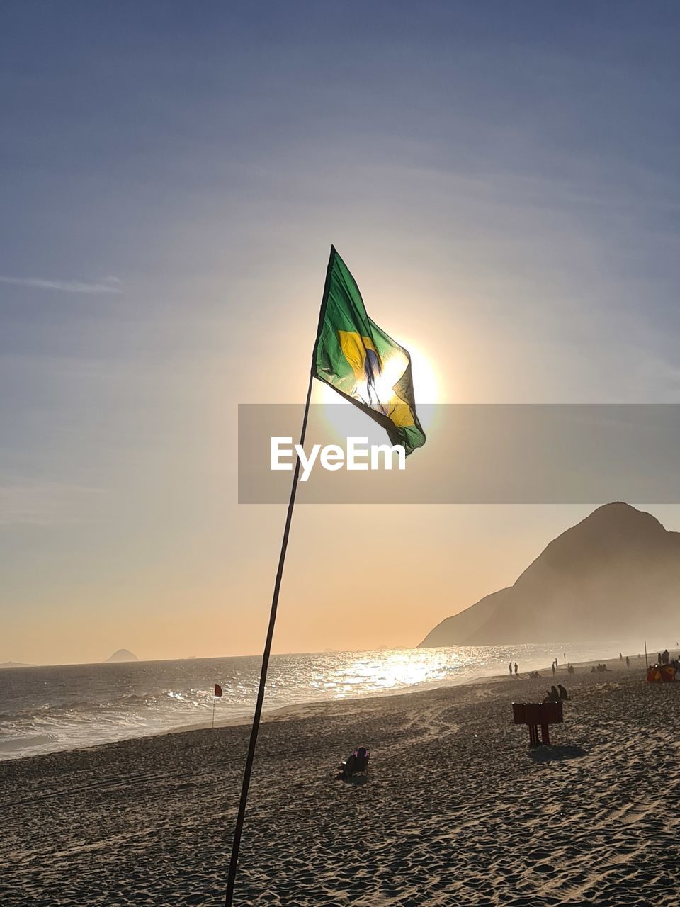 FLAG ON BEACH AGAINST SKY DURING SUNSET