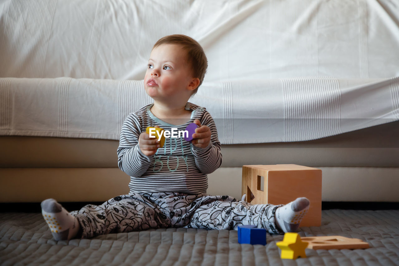 Full length of boy with down syndrome playing on rug at home