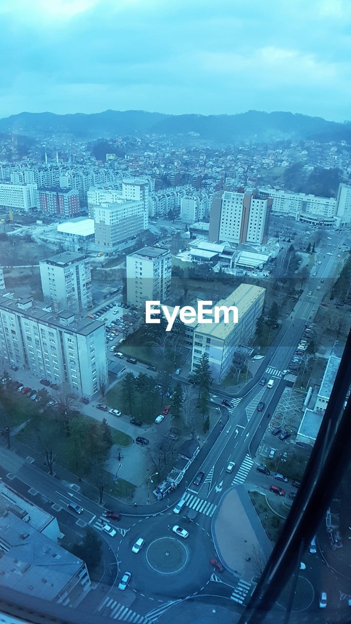 HIGH ANGLE VIEW OF CITYSCAPE SEEN THROUGH WINDOW