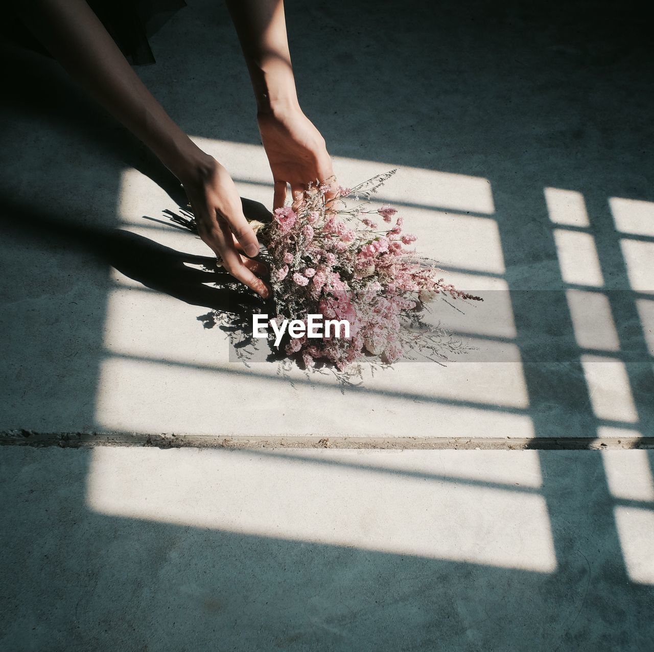 Cropped hands holding bouquet on footpath