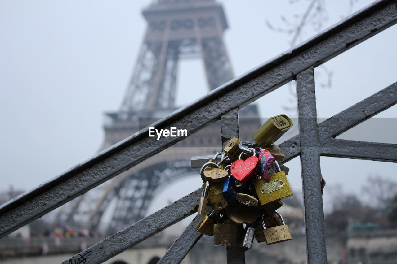 Close-up of love locks on railing against eiffel tower