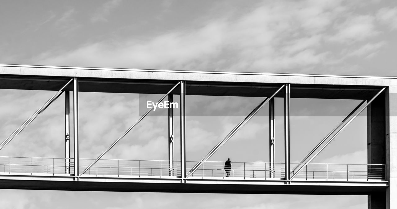 Low angle view of man walking on bridge against sky