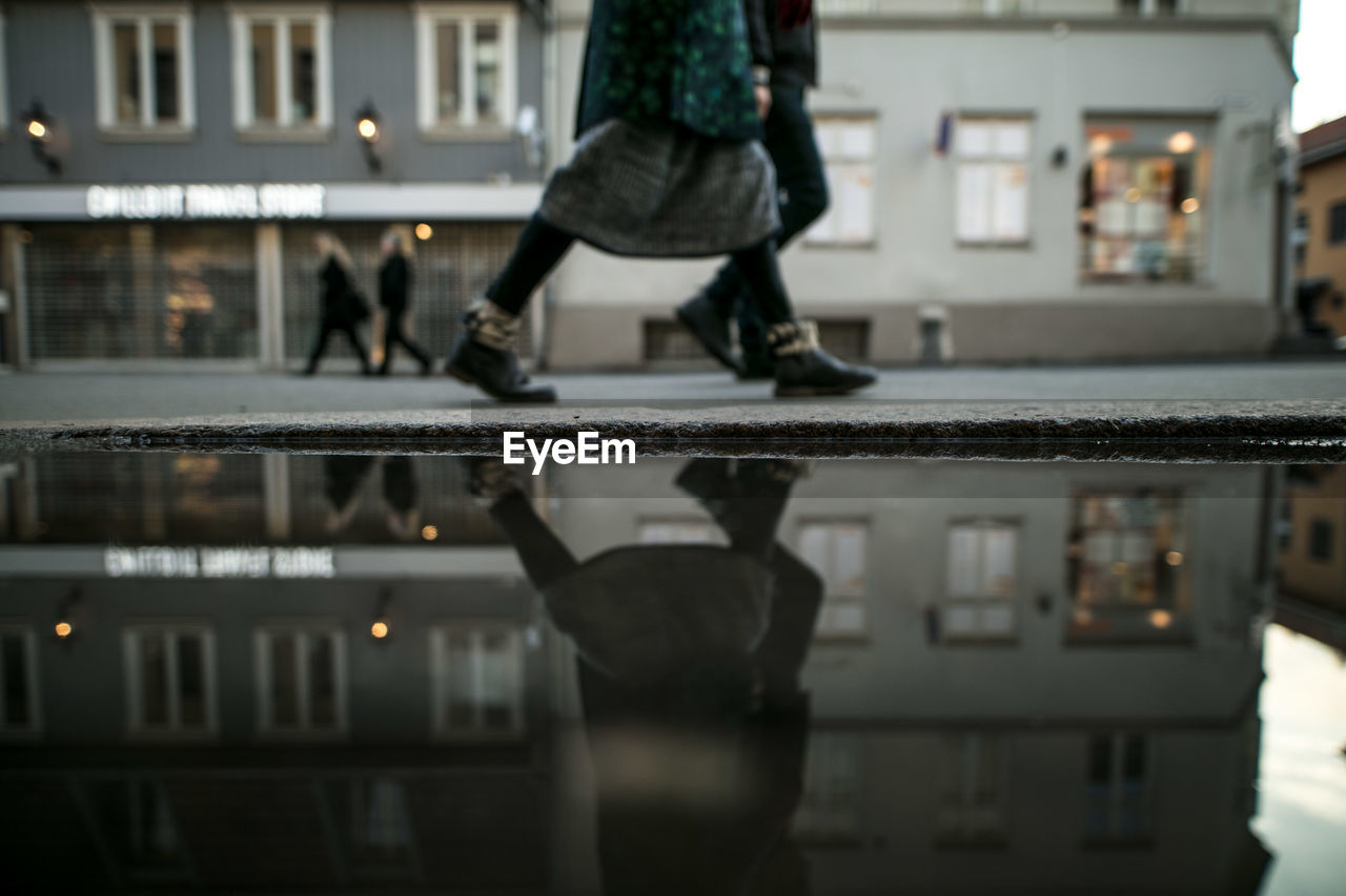 Low section of woman reflecting in puddle