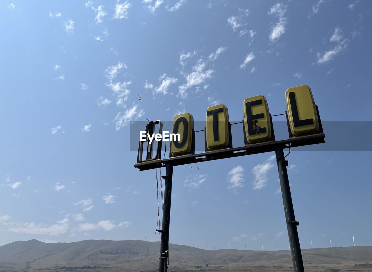 Low angle view of a run down motel sign against sky