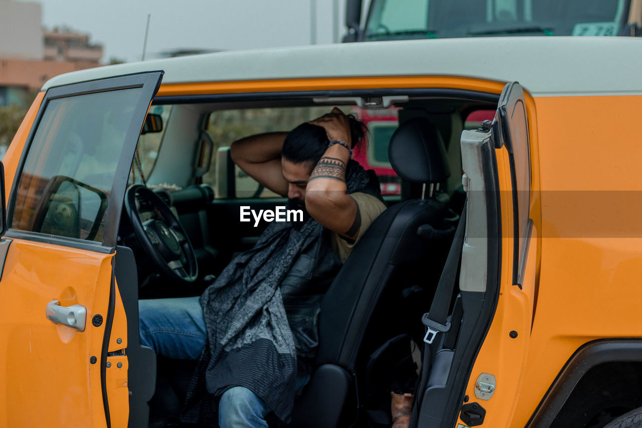 Man tying hair while sitting in car