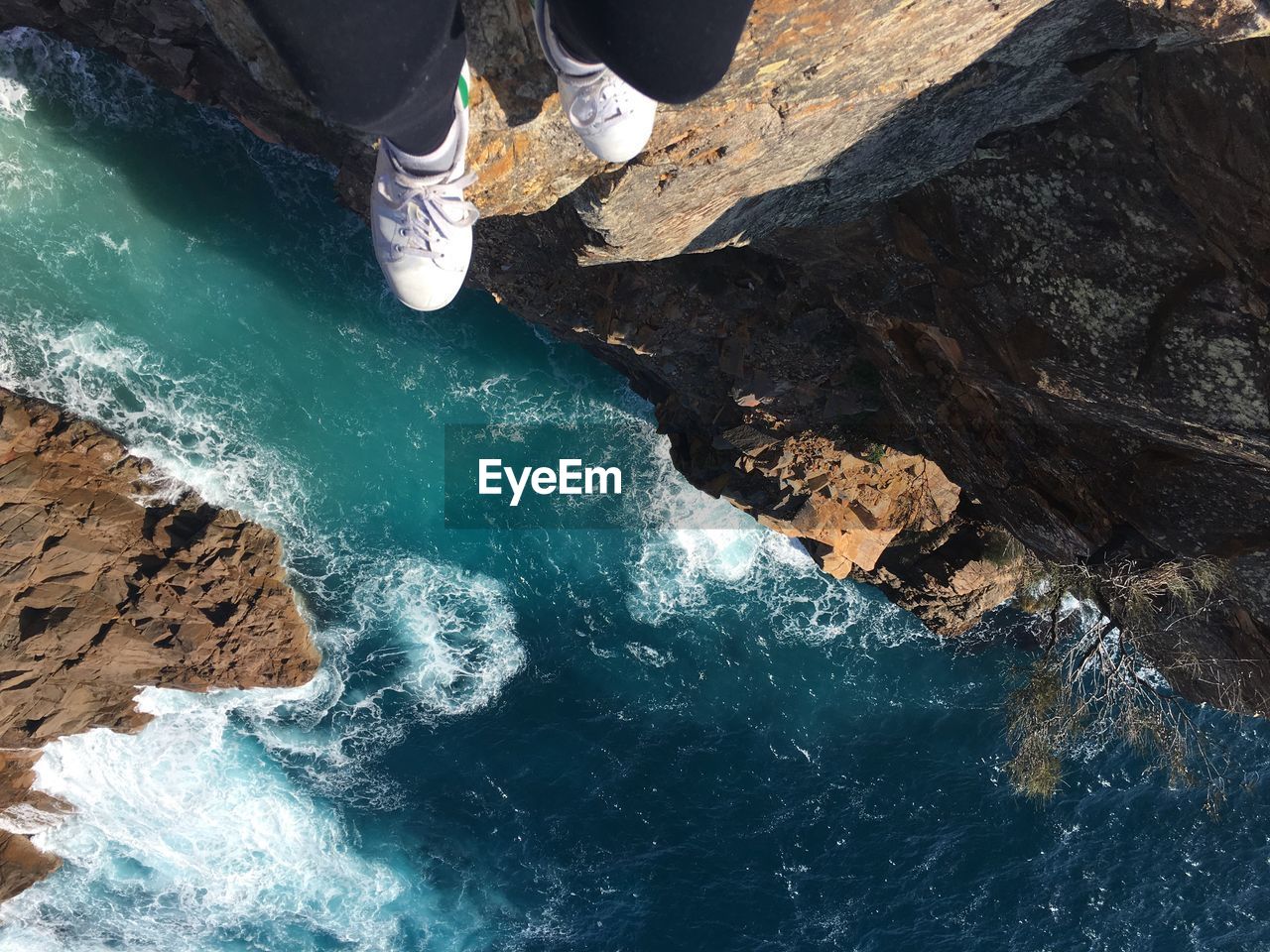 Low section of person on rock formation over sea