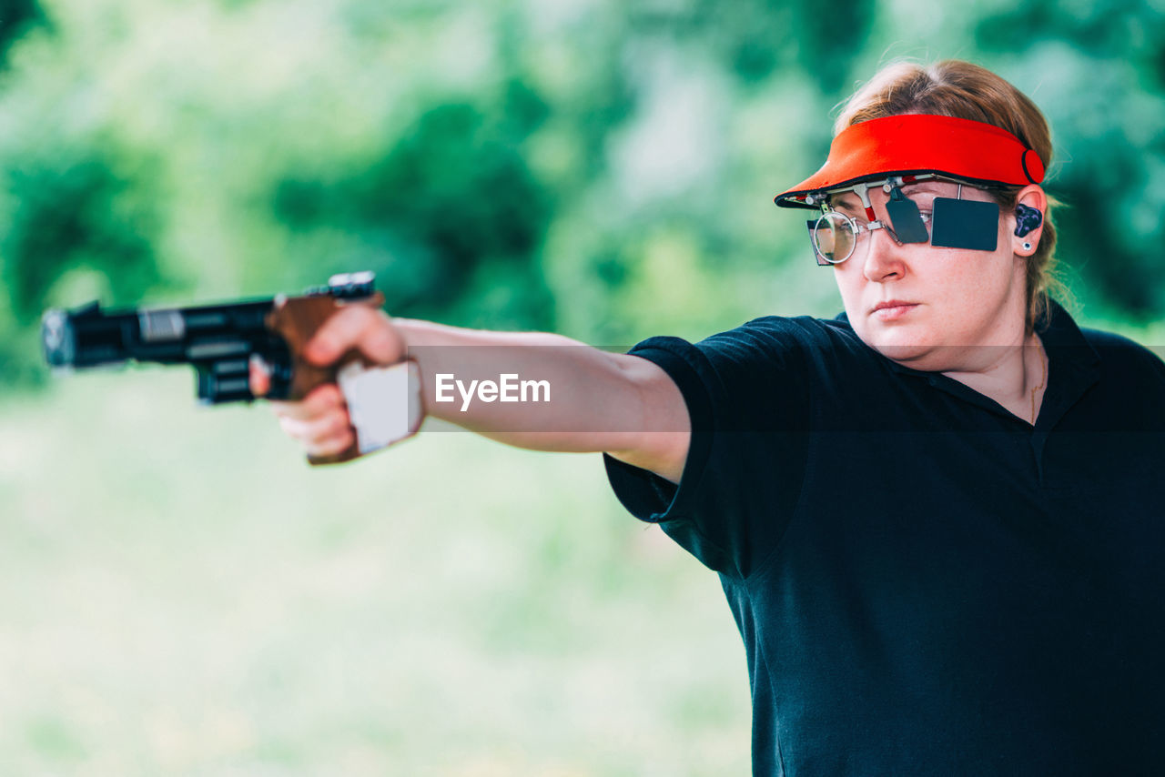 Close-up of woman aiming gun outdoors
