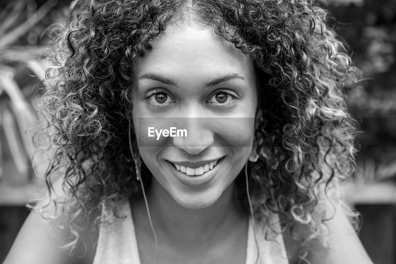 Close-up portrait of smiling young woman with curly hair