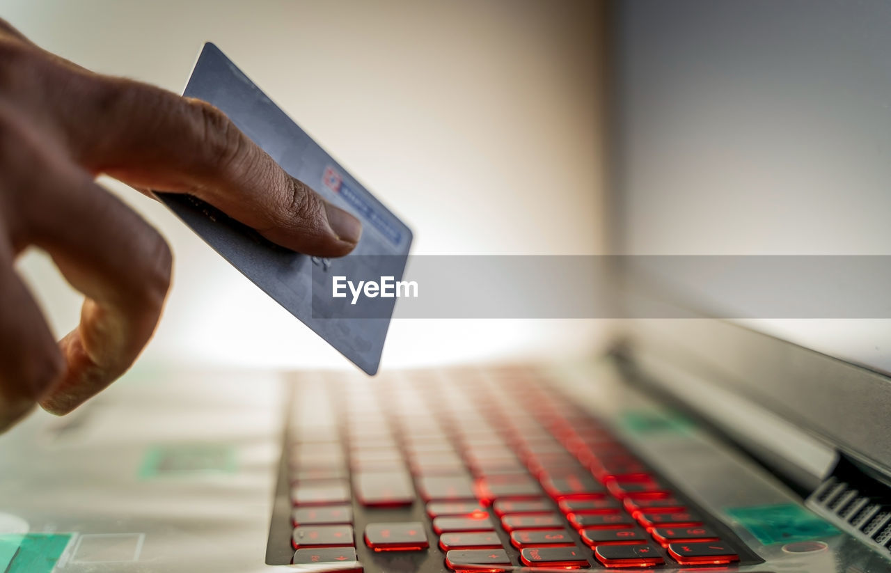 Hand holding credit card and next to pc keyboard for order online shopping via internet