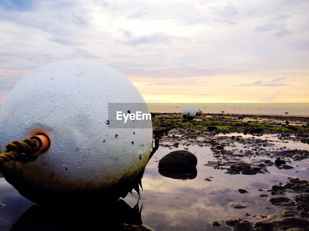 Close-up of buoys on beach against sky during sunset