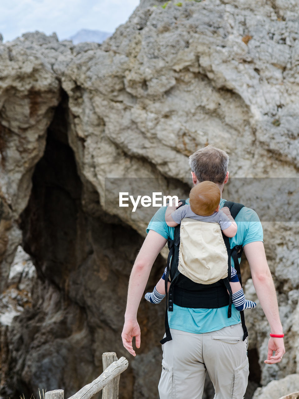 Rear view of man carrying son while walking on mountain