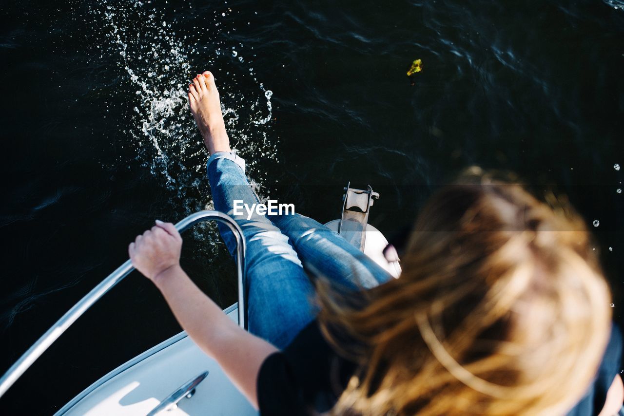 High angle view of woman splashing water while sitting on boat