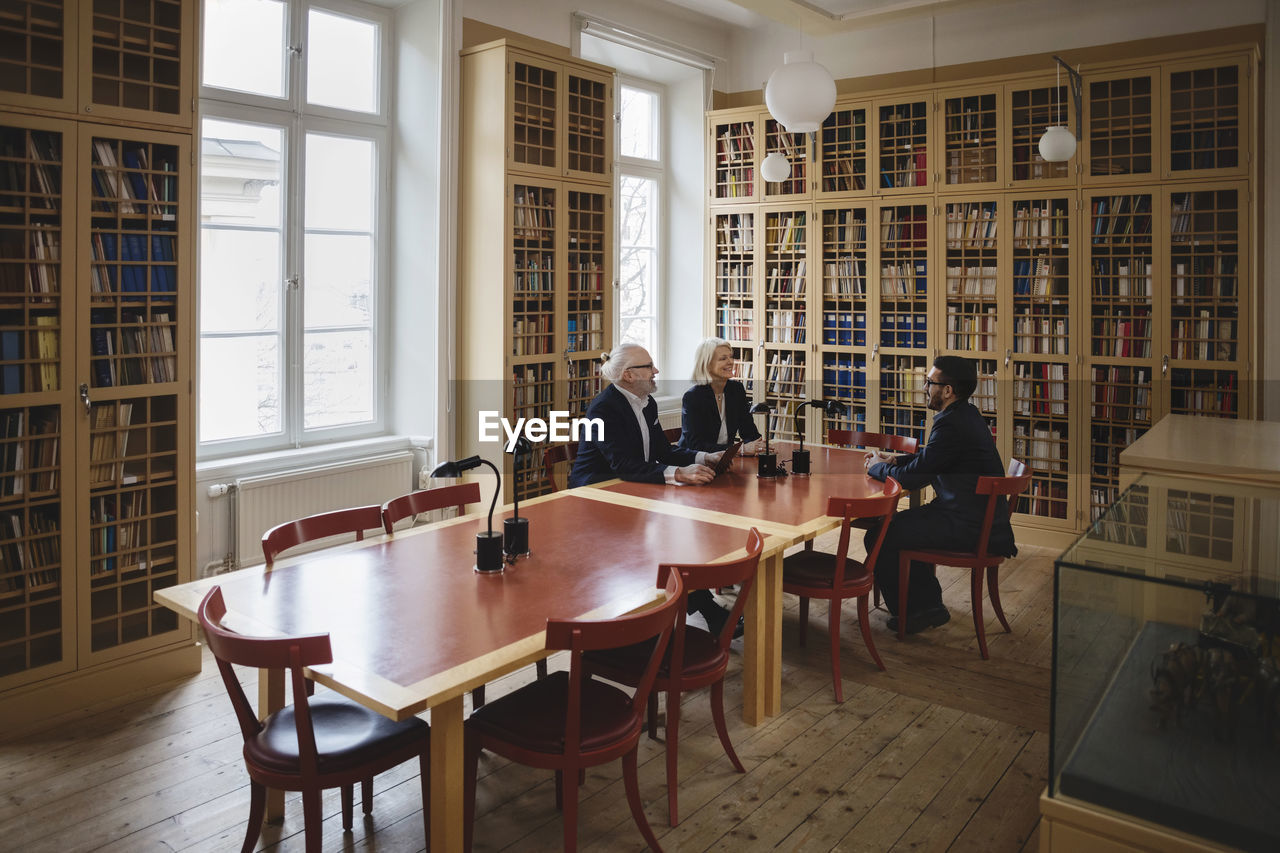 Happy lawyers sitting at table during meeting in board room