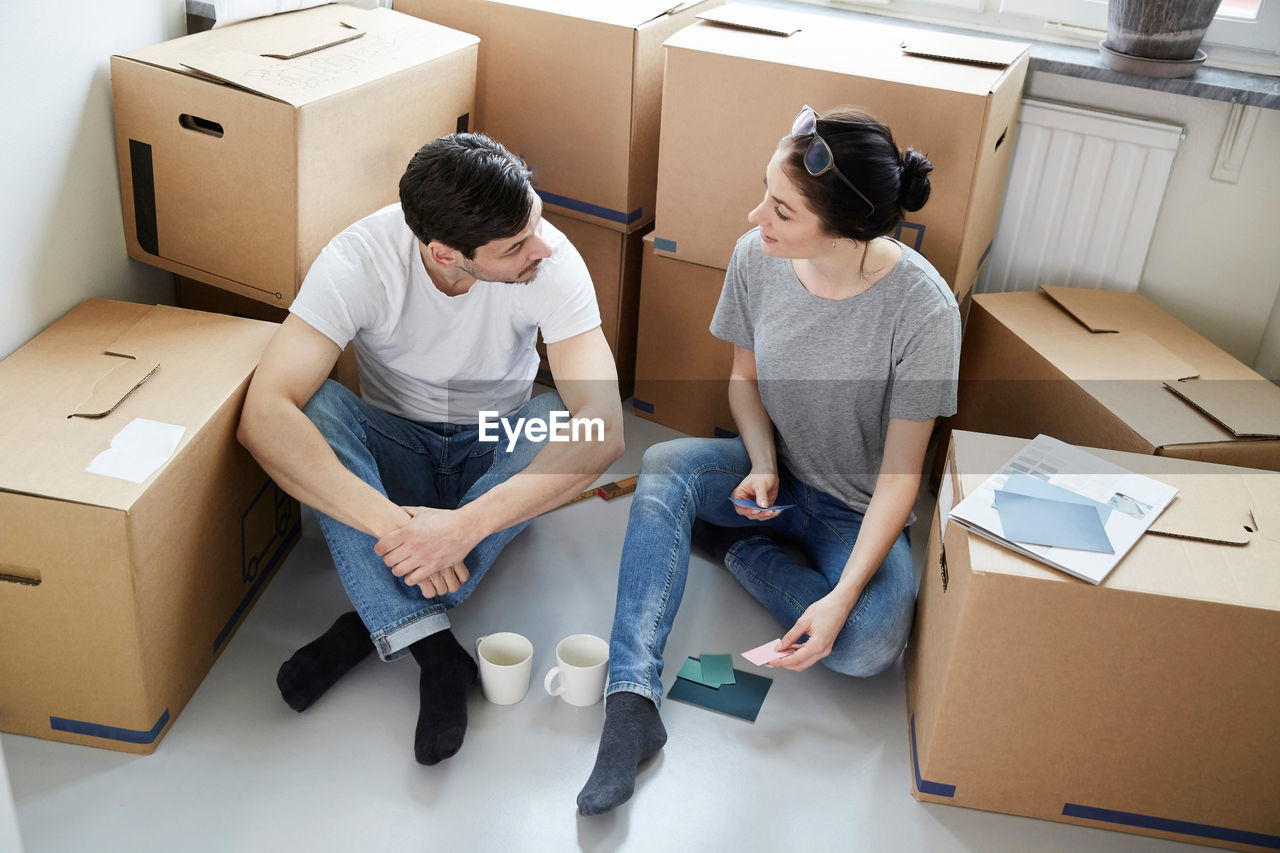 High angle view of couple discussing over color samples during coffee break while moving in new house