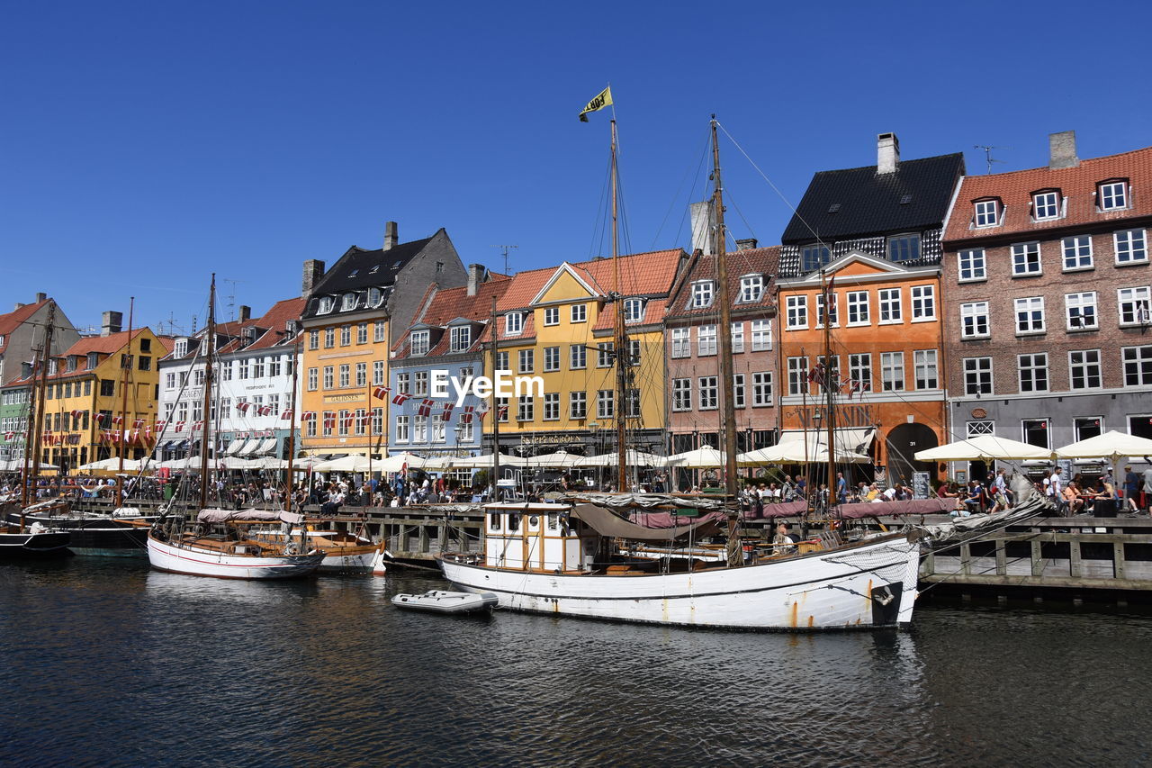 Sailboats moored on canal by buildings against sky in city