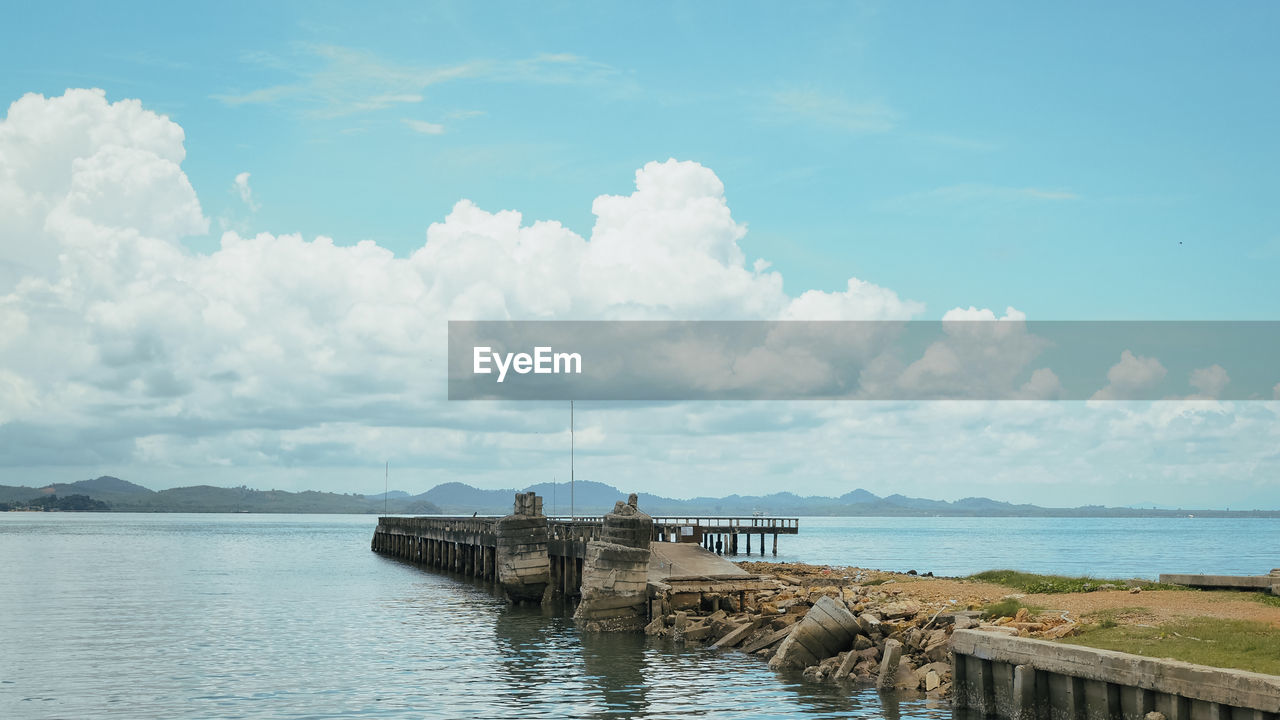 Pier on sea against cloudy sky