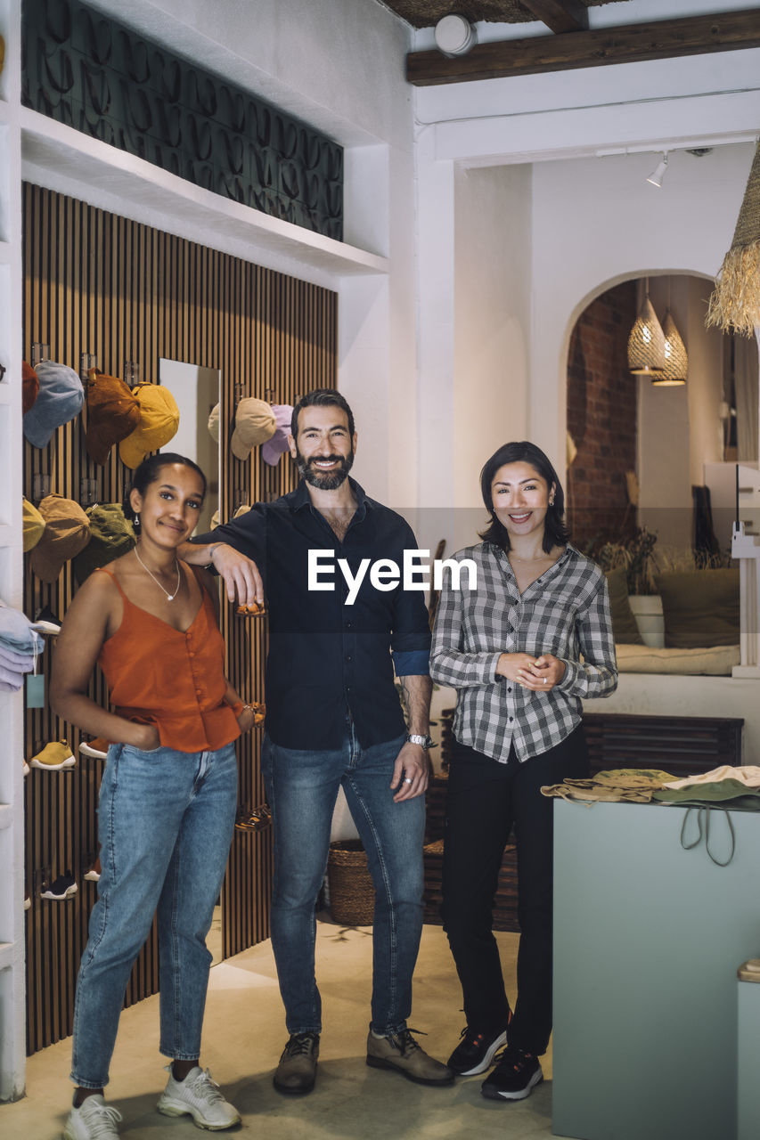 Portrait of multiracial male and female sales colleagues standing together at fashion store