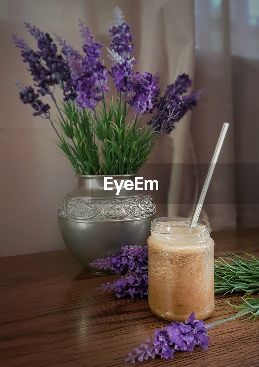 Ice coffee and of purple flower in vase on table