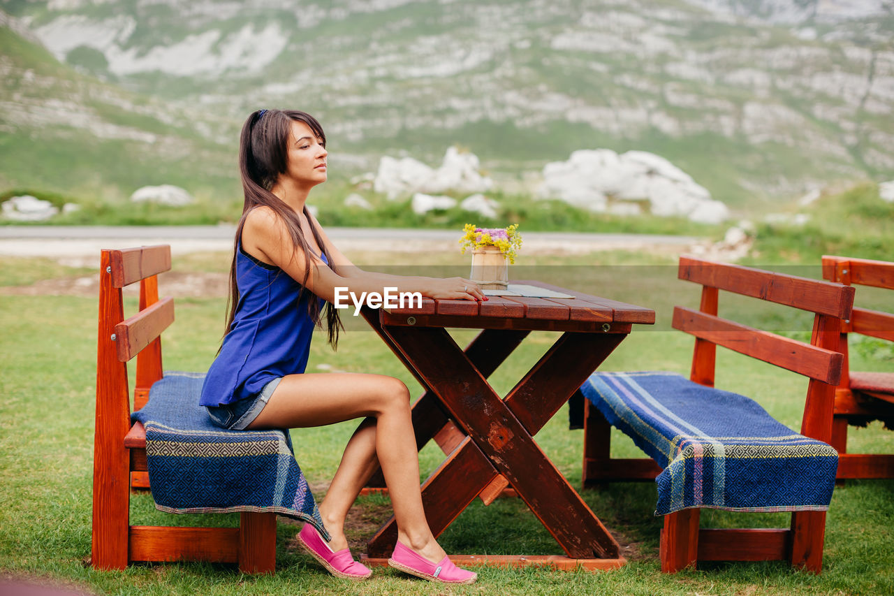 Side view of mid adult woman sitting on bench