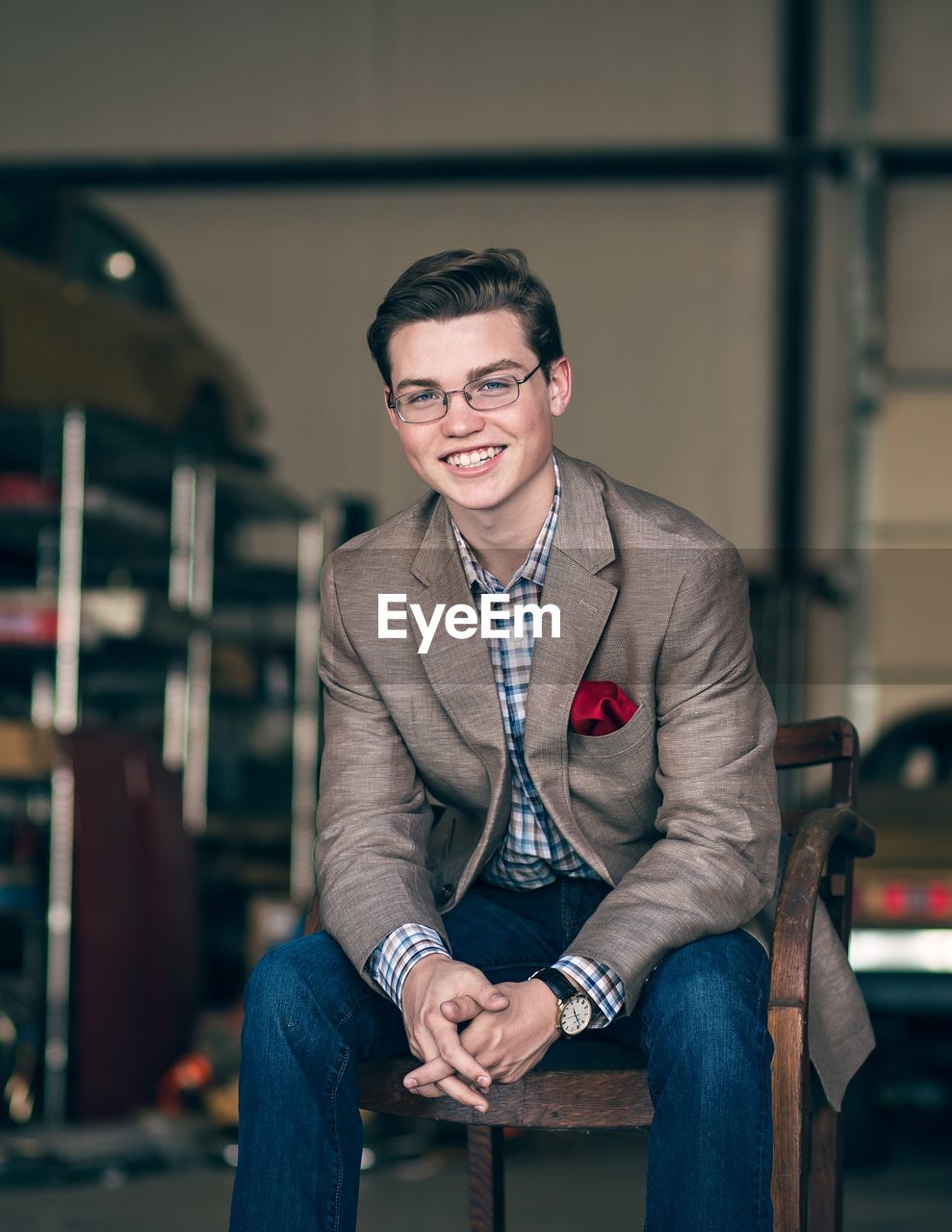 Portrait of young man wearing suit while sitting on chair in industry