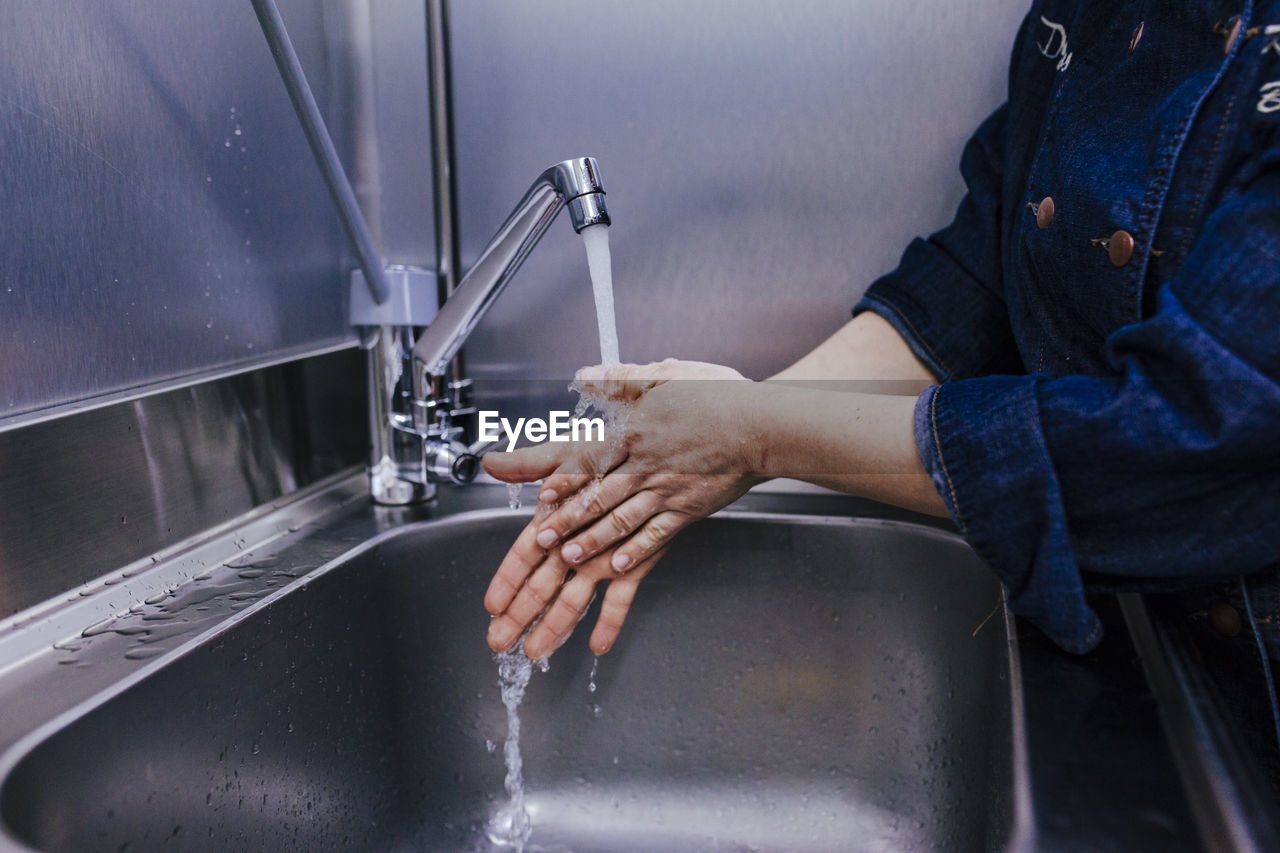 Midsection of woman washing hands in sink