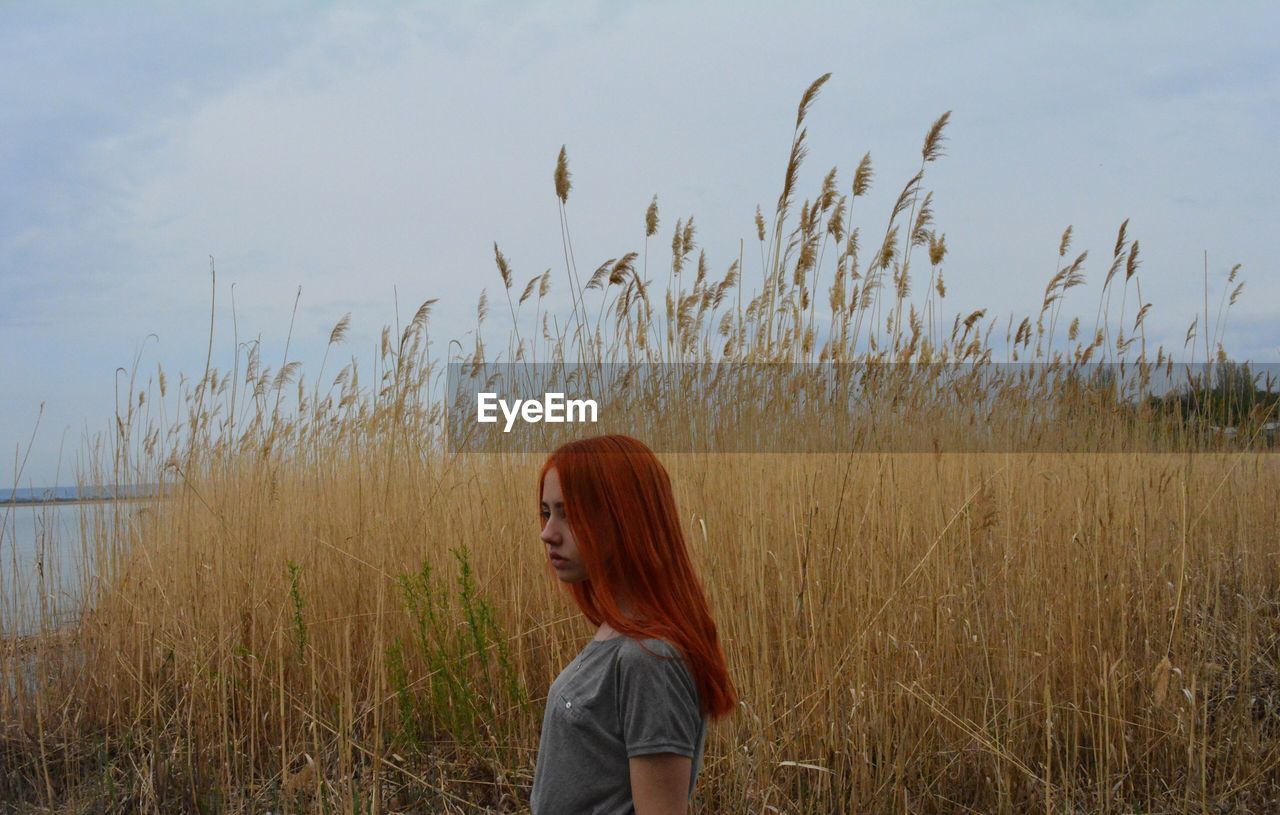 WOMAN STANDING ON GRASSY FIELD