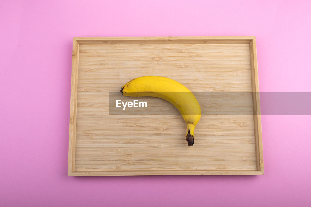 banana, fruit, food and drink, healthy eating, food, indoors, produce, wellbeing, yellow, wood, no people, studio shot, cooking plantain, directly above, colored background, freshness, plant, single object, peel, pink, high angle view, banana peel, still life