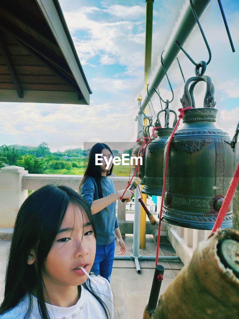 Cute girls standing by bell at temple