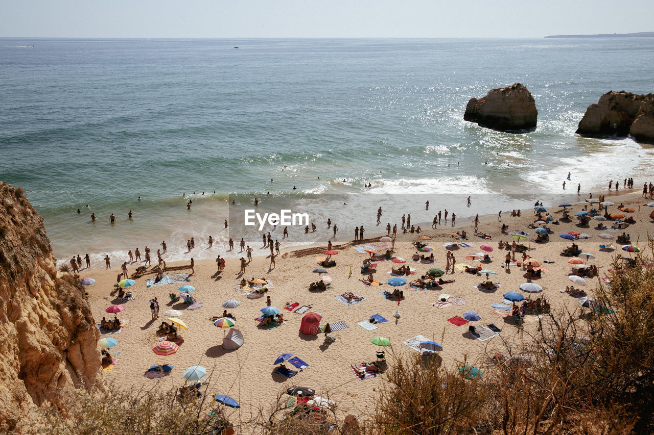 Scenic view of sea against sky and people on beach in portugal. 