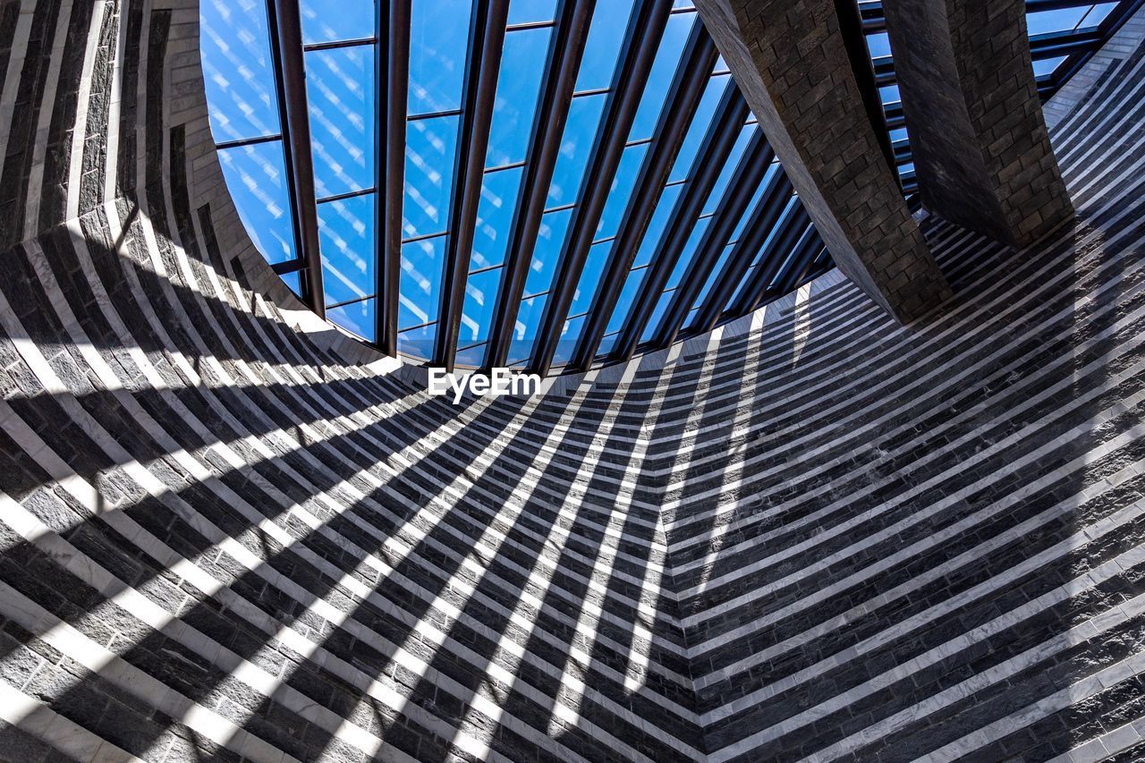 LOW ANGLE VIEW OF MODERN GLASS BUILDING IN CITY