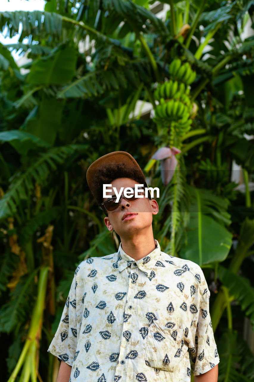 A young guy wearing summer clothing. palm tree as background.