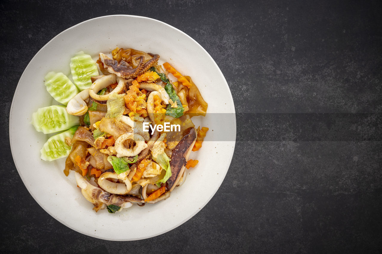 Pad see ew pla muek, thai food, stir fried soy sauce noodle with squid, egg, lettuce, carrot