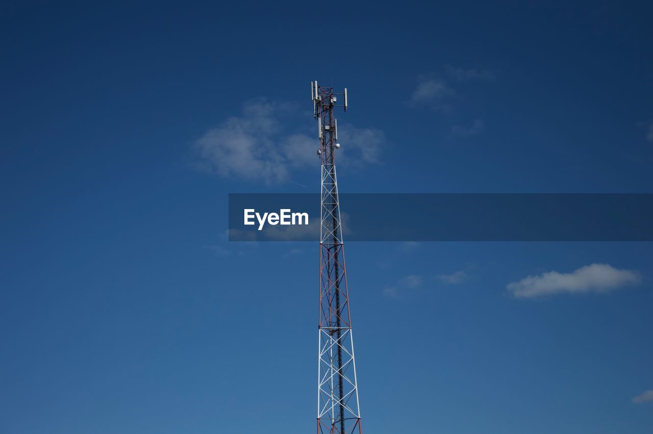 Low angle view of communications tower against blue sky