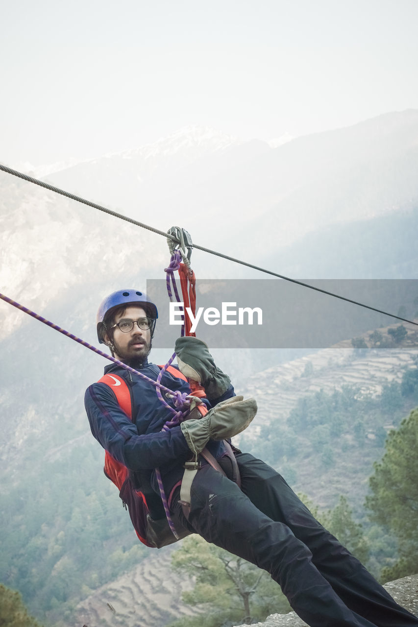 MAN HOLDING ROPE ON MOUNTAIN