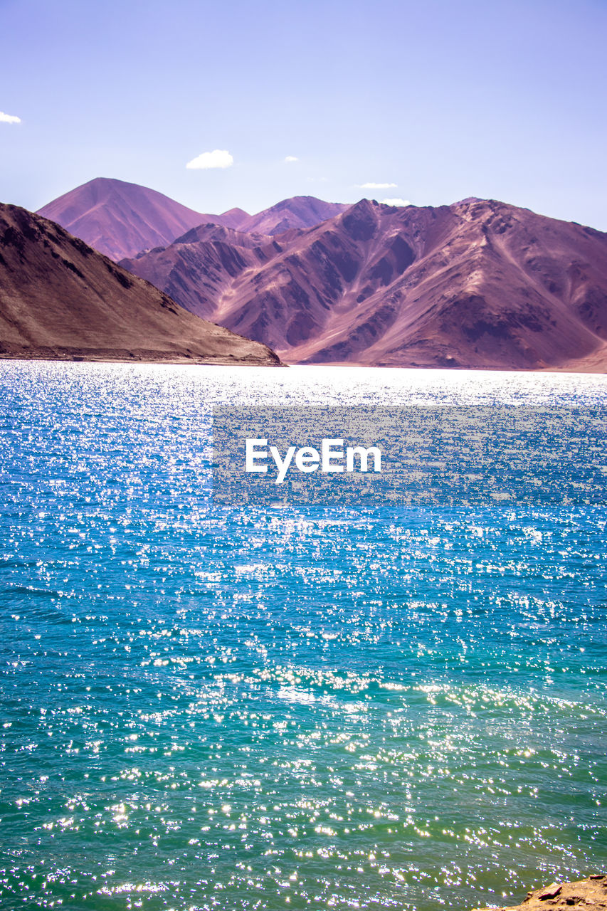SCENIC VIEW OF SEA AGAINST MOUNTAIN RANGE