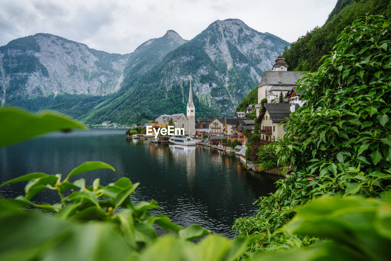 Famous lake side view of hallstatt village with alps behind, foliage leaves framed. austria