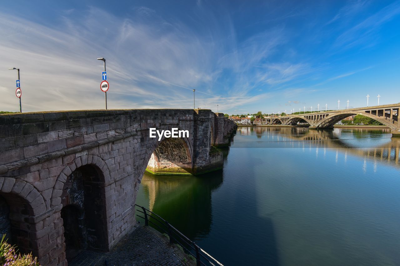 Arch bridge over river against sky