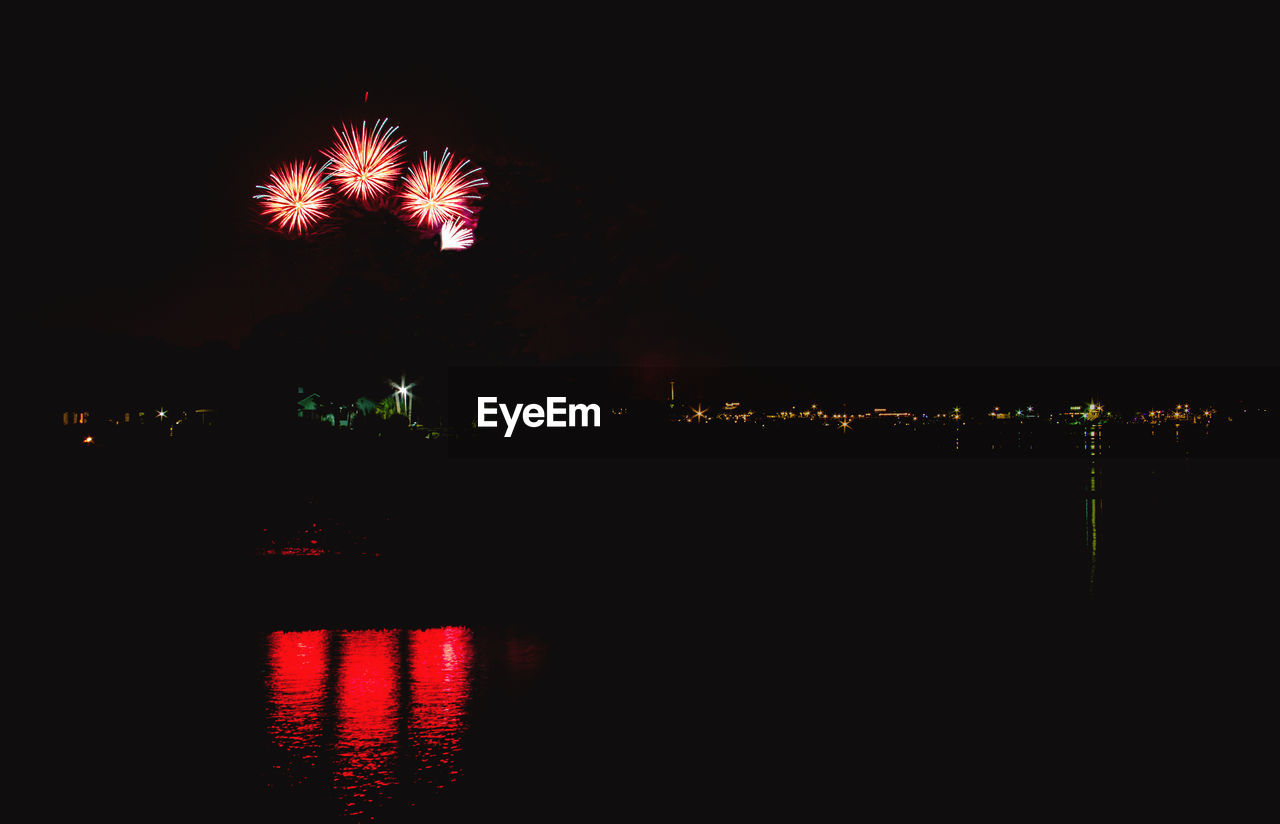 Reflection of firework display on sea at night