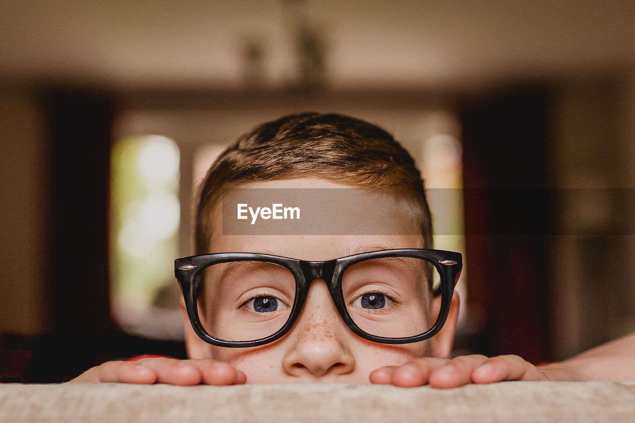 Portrait of peeking boy wearing oversized glasses
