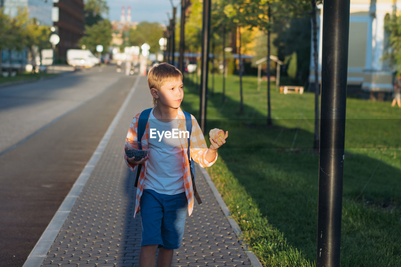 Caucasian boy walking from school wearing school bag. begining of academic year
