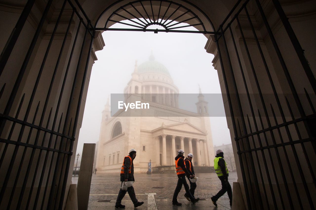 Workers walking against st nichola church during foggy weather