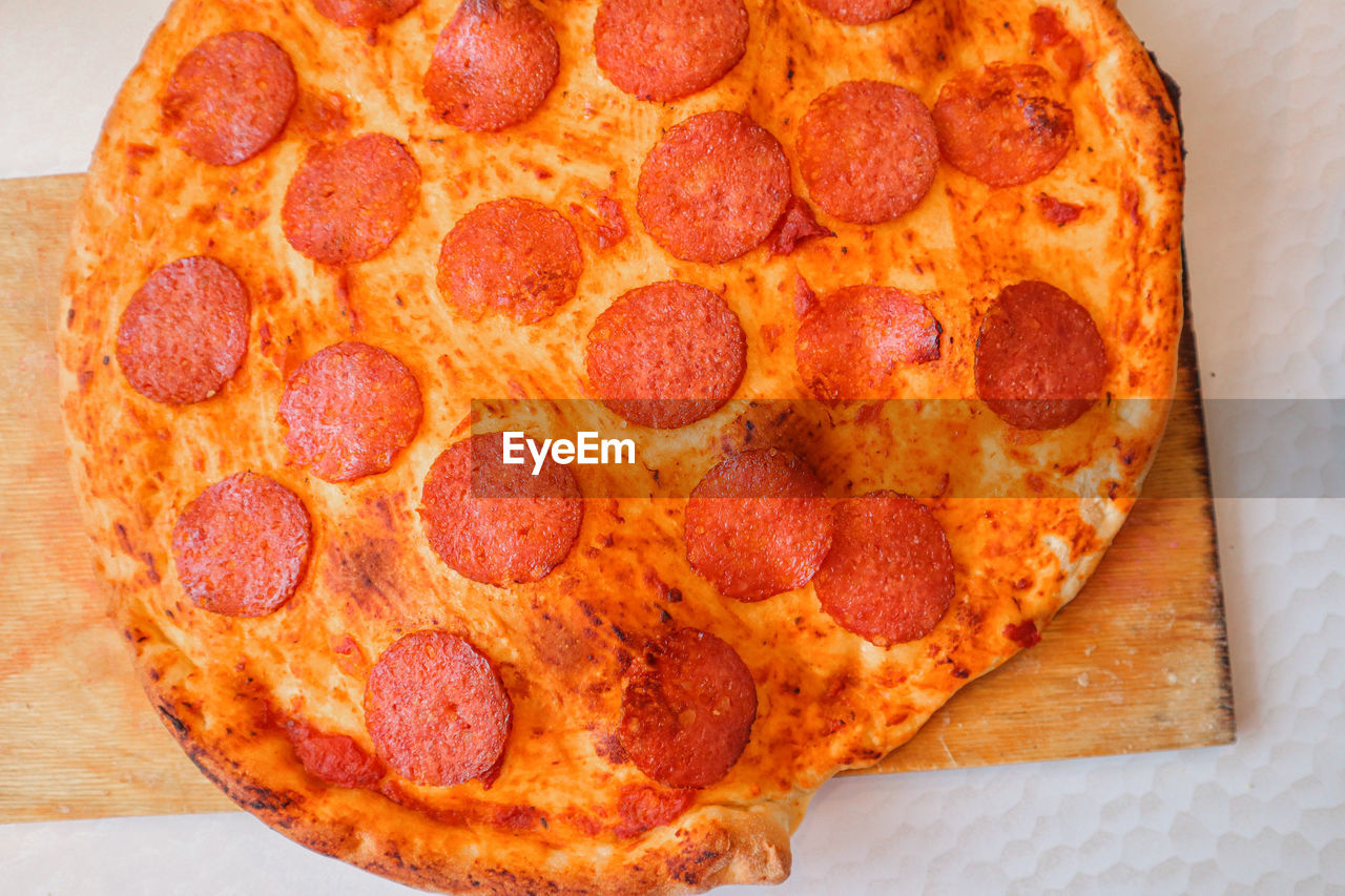 pepperoni, food and drink, food, pizza, fast food, pepperoni pizza, dish, cuisine, sausage, freshness, unhealthy eating, italian food, indoors, high angle view, directly above, no people, baked, circle, geometric shape, meat, cheese, still life, slice, close-up, table, dairy, fruit, shape, salami