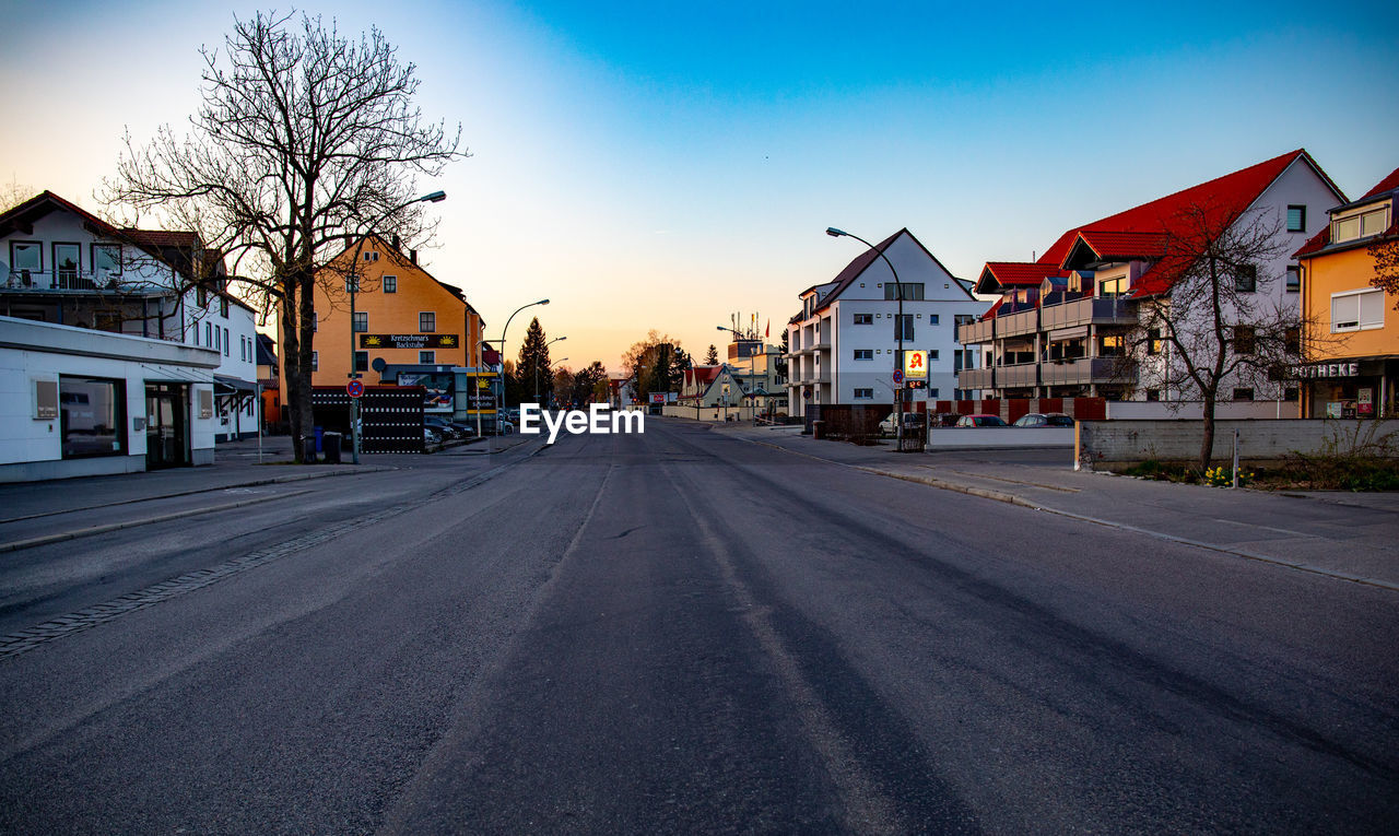 EMPTY ROAD AMIDST BUILDINGS AGAINST SKY