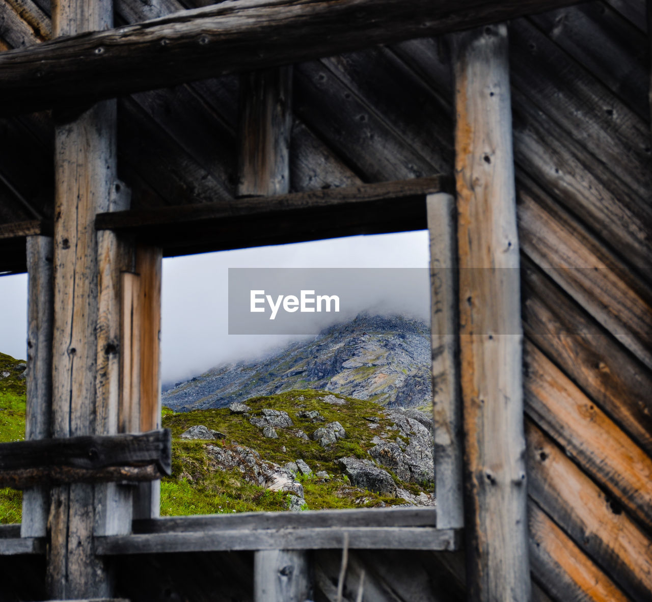 Scenic view of mountain seen through wooden window